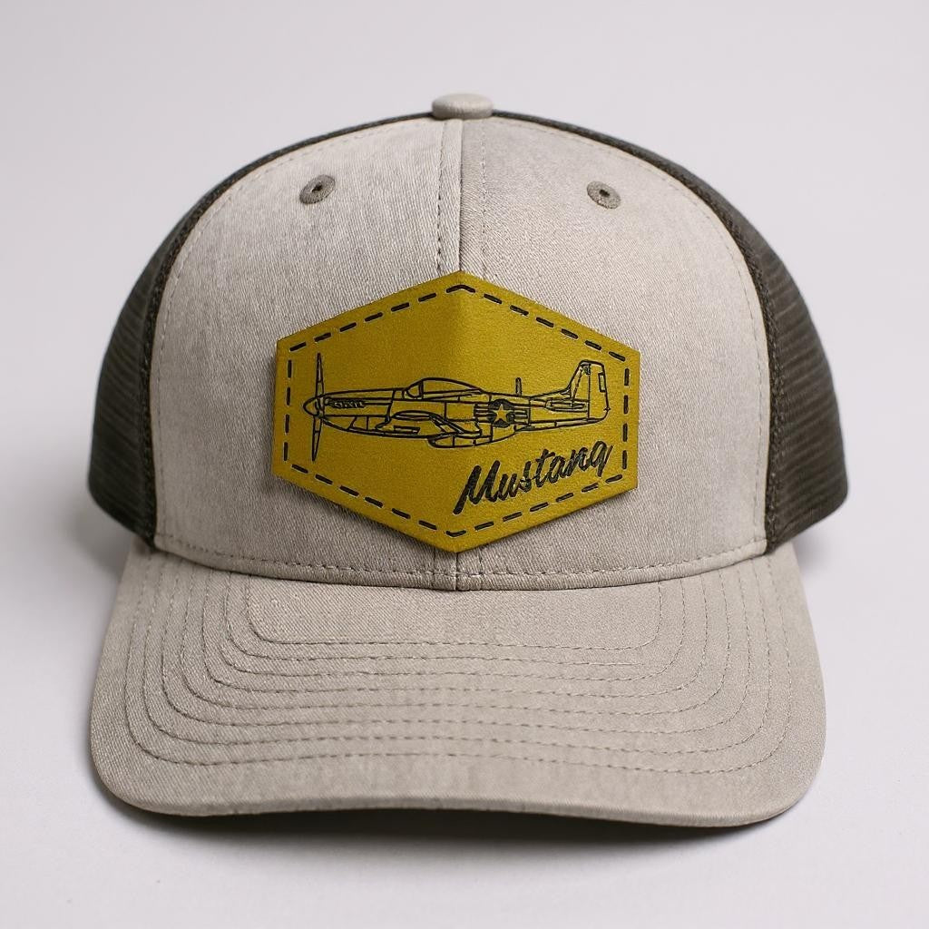 Gray and black trucker hat with green patch featuring the word "Mustang" and the airplane airplane design on a light gray background