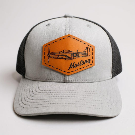 Gray and black cap with brown patch featuring an airplane design on a white background