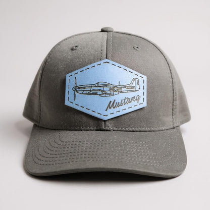 Black trucker hat with a blue patch featuring an airplane and 'Mustang' text on a white background.