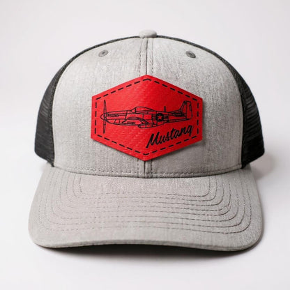 Gray and black trucker hat with a red textured patch featuring an airplane and 'Mustang' text on a white background.