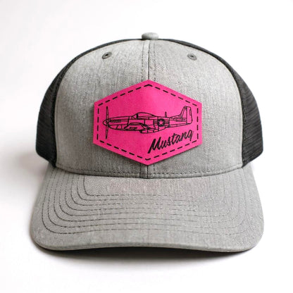 Gray and black trucker hat with a pink patch featuring an airplane and 'Mustang' text on a white background.