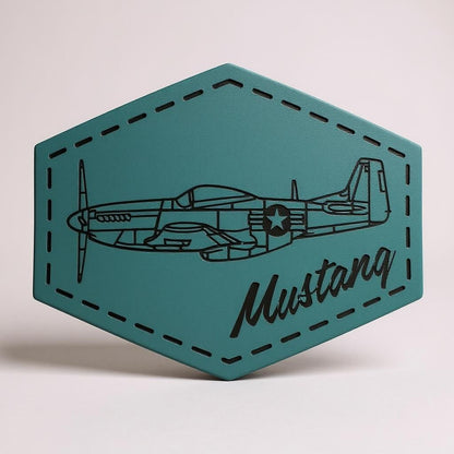Hexagonal teal leather patch with a black airplane design and 'Mustang' text on a light gray background